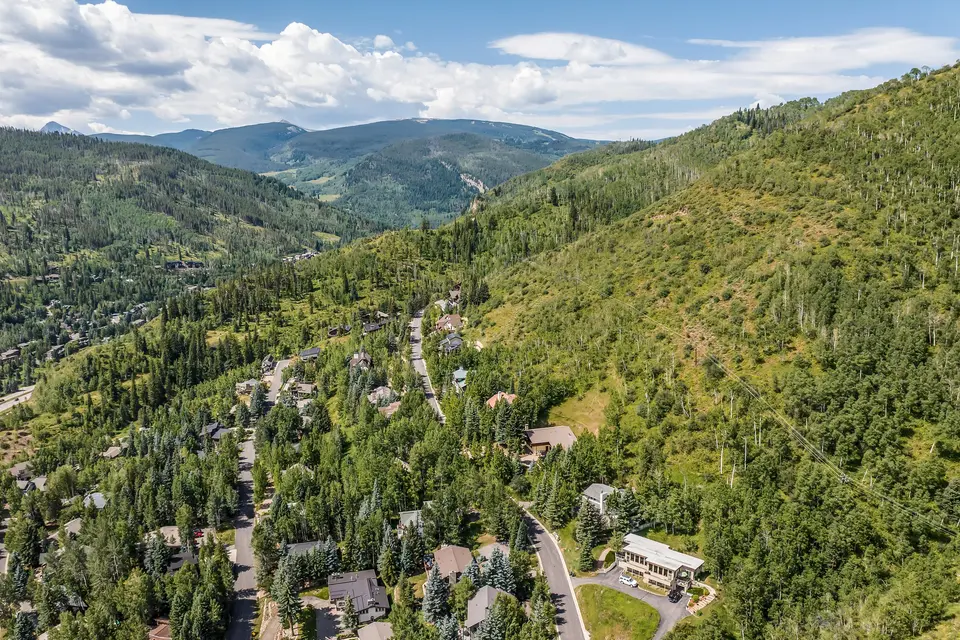 Aerial view of a Vail Valley neighborhood among green forests below the mountains