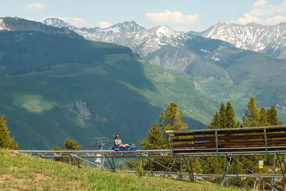 Rider on a mountain coaster with jagged peaks beyond